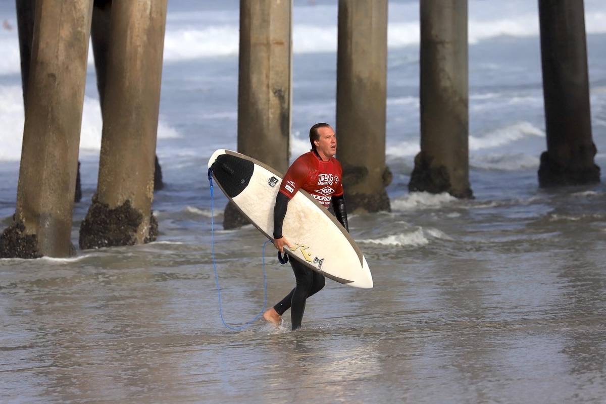 Bjorn carrying surfboard by the pier